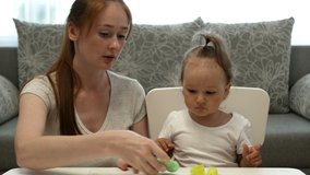 Cute little girl and attractive young mother play plasticine. Daughter and mother spend time together and make plasticine figures.