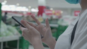 Close up woman wear protective mask using smartphone standing inside the mall supermarket, paying bills through phone 4g 5g technology, promtpay service, virus pandemic, shopping at grocery  - Powered by Shutterstock - Get 15% off with code: PIKWIZARD15