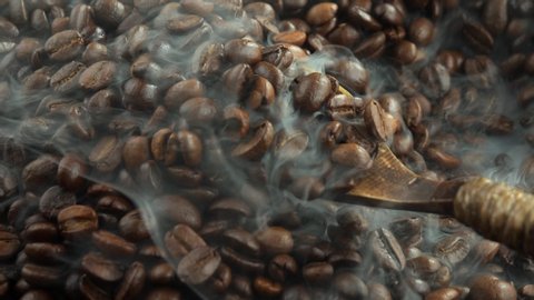 Coffee beans roasted in a skillet with smoke.