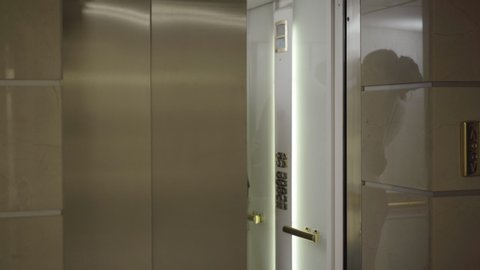 Young Caucasian man and woman hugging and kissing on business center. Elevator door opens and embarrassed couple walking out. Portrait of passionate colleagues flirting in office.