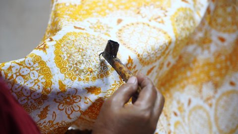 Close Up hand to make batik with canting on the yellow colour fabric