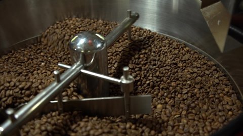 the process of roasting fresh fried coffee beans. Processed coffee beans are mixed around an oven cooling plate.