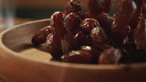 In a beautiful light, dried date fruit fall into the wooden plate in slow motion. 4K,Very close up, phantom camera,900 fps video.