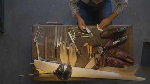 Top view shoemaker sews shoes. Close up shoe manufacturing workshop. Handmade work shoes. Cobbler make shoes to order. Finish job