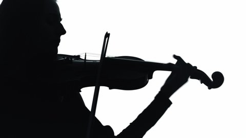 Young woman playing violin in white studio. Silhouette