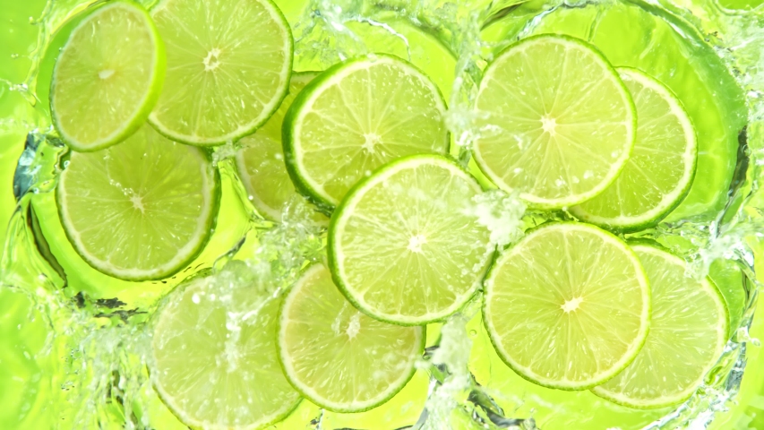 Super Slow Motion Shot of Lime Slices Falling into Water on Green Background at 1000fps. Royalty-Free Stock Footage #1057490590