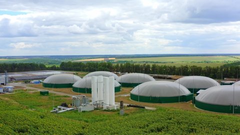 Organic biofuel plant on green field. Modern biogas plant among nature in summer. Biomass production. Innovative storage tanks for biogas.