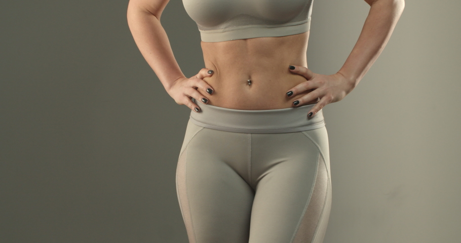 Sports, body shape and fitness concept. Close-up of female abs and bottom. Sportswoman in leggings turning sideways, showing buttocks gluteus and thighs workout progress after gym | Shutterstock HD Video #1057493446