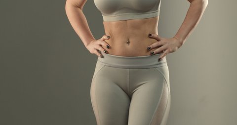 Sports, body shape and fitness concept. Close-up of female abs and bottom. Sportswoman in leggings turning sideways, showing buttocks gluteus and thighs workout progress after gym