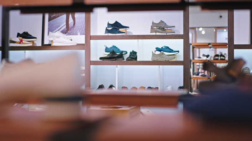 Beautiful asian woman shoes consultant and the customer guy have a discussing about the shoes in a shoe shop lady take some shoes from the shelves and giving to the customer. 