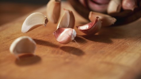 The garlic passes in front of the camera in slow motion on a wooden background. Macro, 4K, Phantom Camera, Super Close-up.