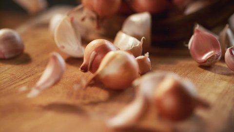 Garlic and small onions pass in front of the camera on the wooden floor. Macro, 4K, Phantom Camera, Super Close-up.