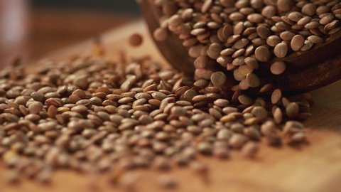 In a beautiful light, Green lentil grains fall into the wooden plate in slow motion. 4K,Very close up, phantom camera.