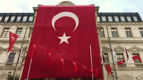 giant Turkish flag hung on the building next to the Gothic-style architecture waving small Turkish flags hung sequentially May 19 Youth and Sports Day celebrations 4K video capture Istanbul Turkey.