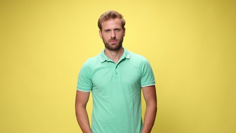 casual young model smiling, holding hands in pockets, crossing arms and standing on yellow background