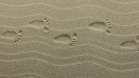 Zoom. Human prints on the sand dunes. Crane shot.