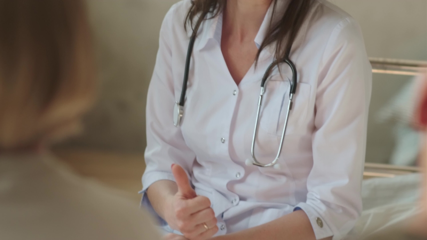 Beautiful brunette medic woman in a white coat carefully communicates with patients, portrait. Female doctor talks with a patient, says the diagnosis, prognosis for treatment. Royalty-Free Stock Footage #1057520290
