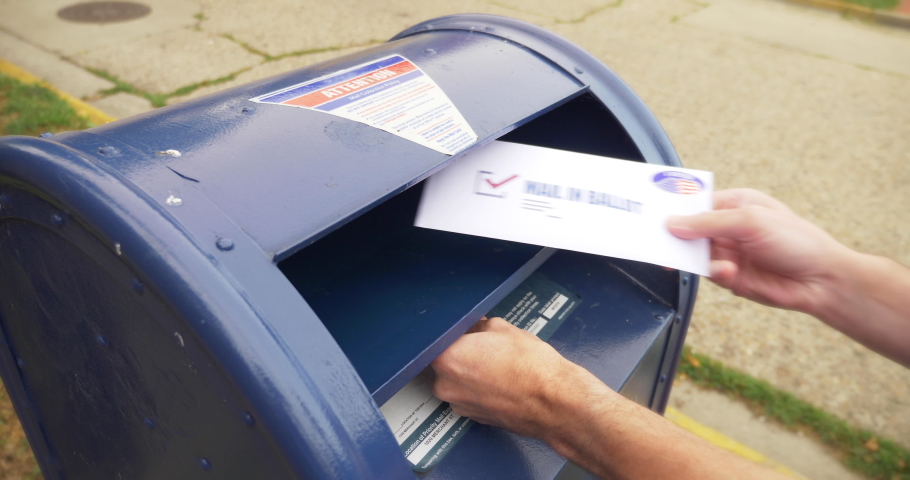 Circa August, 2020 - A man drops an absentee or mail-in ballot in the mailbox.  	