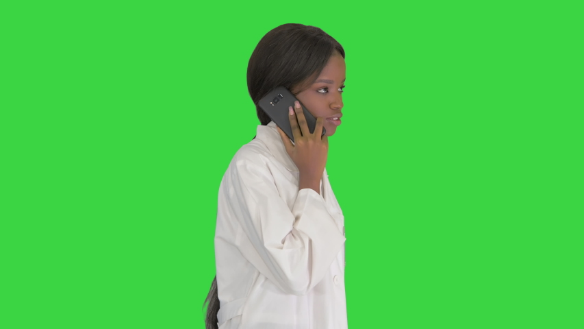 African american female doctor talking on the phone while walking on a Green Screen, Chroma Key.