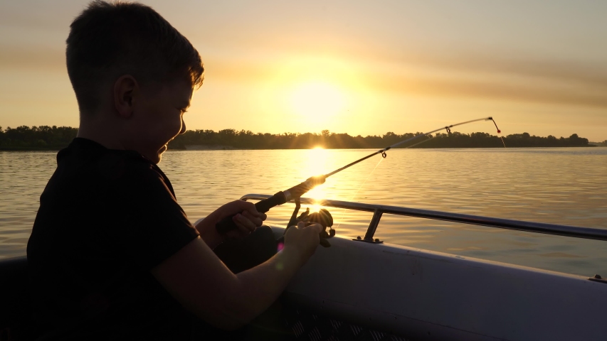 A boy on a fishing trip caught a fish.Fishing on the lake from a boat. Fishing rods in sunlight. Fishing rest concept.	 Royalty-Free Stock Footage #1057527859