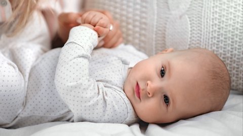 Closeup caring mother hand stroking head of cute little baby relaxing lying on bed. Adorable sleepy toddler enjoying happy childhood and mom love feeling tenderness. Shot with RED camera in 4K