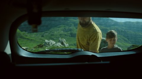 Happy father and son open car trunk and take backpack gets things out against mountain landscape in Montenegro. Family vacation 
