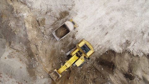 Aerial top down view of an excavator loading rock and earth on a very large dump truck, Loaded With Ore .