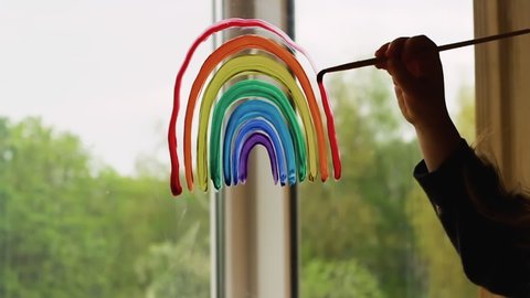 Painting rainbow on window during Covid-19 quarantine at home. Stay at home social media campaign for coronavirus prevention. Catch the rainbow.