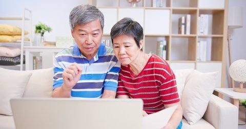 asian elder couple calculate expenses finance with laptop and discuss retire plan together at home