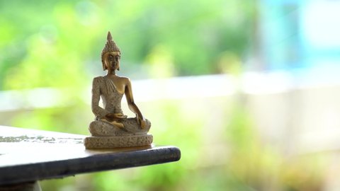 Meditating buddha with green & rain background. Buddha bronze idol in a mindfulness meditation posture