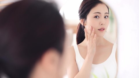 Beautiful asian woman looking at a mirror.