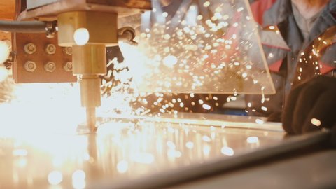A professional worker behind protective glass works with a metalworking machine. Craftsman, miller or engineer. Sparks fly in the process of work, close-up. Slow motion