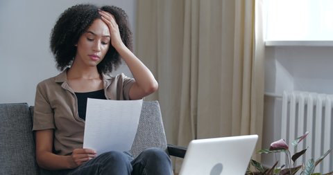 Young woried curly African girl receives letter in mail with bad news, medical tests, learns about failed exams, holds refusal notice in her hands, feels sad displeasure resentment, upset female face