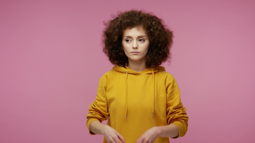 Curious  young woman afro hairstyle in hoodie looking through hands binocular gesture, zooming observing distance, expressing surprise shock happiness after seen discovery. indoor studio shot isolated Royalty-Free Stock Footage #1057547122