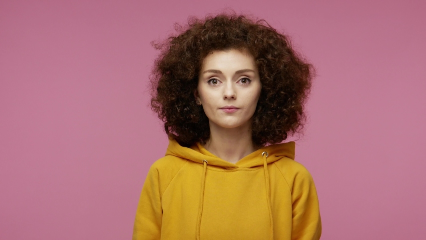 Oh my god wow! Amazed excited  young woman afro hairstyle in hoodie raising hands in surprise looking at camera with big eyes, shocked by sudden victory. indoor studio shot isolated on pink background Royalty-Free Stock Footage #1057547125