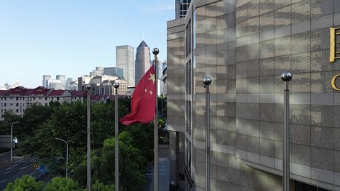 Shanghai, China - Aug 1, 2020: Chinese national flag in front of The China Development Bank (CDB). Red five star flag of China and the downtown aerial view in the background. National flag in the wind