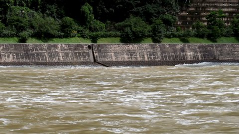 Flooded river restrained by concrete wall flowing rapidly after torrential rainfall 