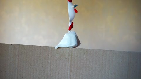 toy chicken made of plastic spoon, paper napkin and plasticine moves behind a cardboard screen