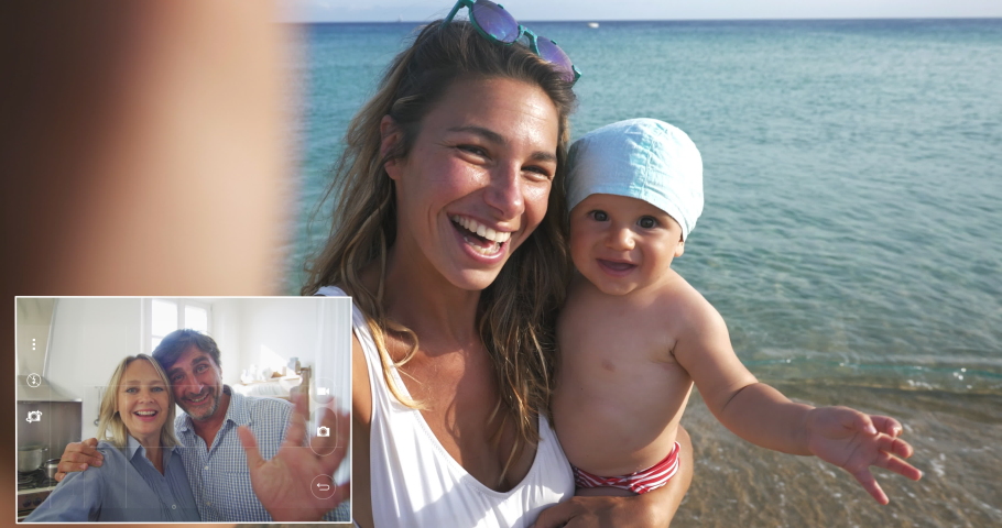 A happy carefree smiling neo mother and her newborn baby making selfie or video call to father or relatives on a beach with seaside in a sunny day. | Shutterstock HD Video #1057566574