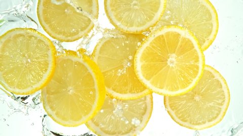 Super Slow Motion Shot of Lemon Slices Falling into Water on White Background at 1000fps.