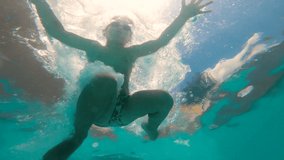 From inside the pool, young caucasian boy jumps into the pool and dives with swimming goggles. 5 year old kid swimming and having fun in summer on a sunny blue cloudy day. Vacation concept.  - Powered by Shutterstock - Get 15% off with code: PIKWIZARD15