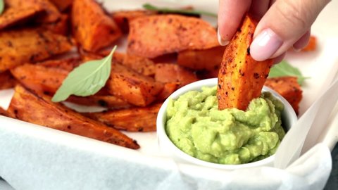 Baked sweet potato wedges with guacamole. Healthy vegan food concept.