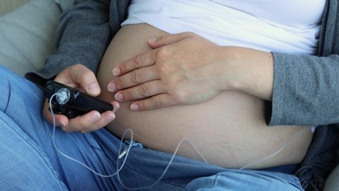 Pregnant woman operates insulin pump. Modern diabetes treatment through insulin given by a drainage mounted on belly.