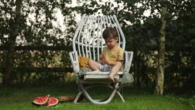 little boy eating watermelon sitting in the garden
