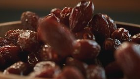 Very Close-up.In a beautiful light, dried date fruit fall into the wooden plate in slow motion. Macro,Phantom Camera,900 fps video.