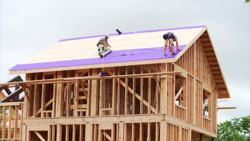 Timelapse of tilers covering the roof with violet layer. Frame house under construction Royalty-Free Stock Footage #1057584175
