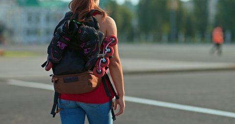 Teenager carries a backpack with roller skates to skate. Teenager goes to roller coaching. Close-up. 4k, 10bit, ProRes