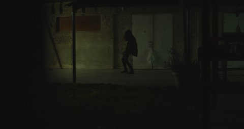 Zombie woman walking through passage near the building at night. Woman transformation into zombie concept. Horror movie style shot. Handheld, cinematic look. BMPCC 4K
