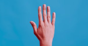 Trauma of hand. Male hand pulsating with red, carpal tunnel syndrome, blue studio background
