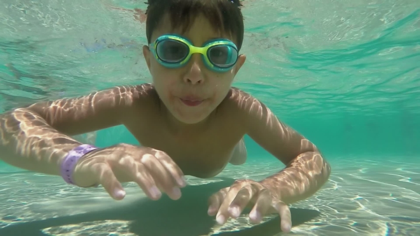 Children in swimming goggles are swimming underwater in the pool | Shutterstock HD Video #1057587232